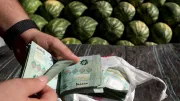 A watermelon producer counts cash bills at a fruit and vegetables outside Beirut