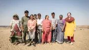 A group of people stands in a dry field in India