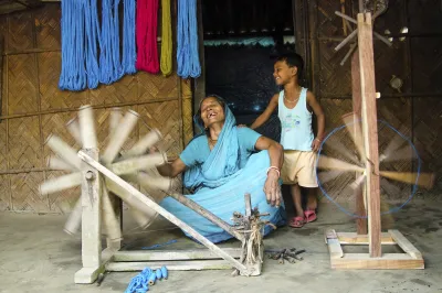 An Indian woman teaching a young boy how to spin thread