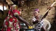 Two women stoke a fire