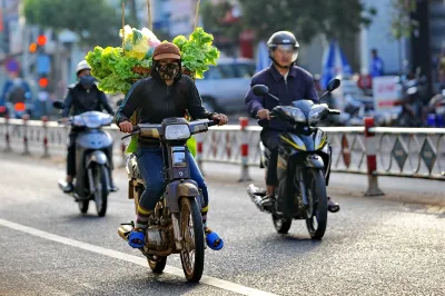 Vietnamese vendors ride on motorbikes with goods