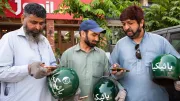 Gig workers in Pakistan look at their smartphones