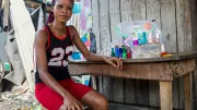 A young woman sits beside her nail salon
