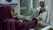 A woman accepts a mobile money payment from another woman