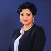 headshot of woman in dark jacket against blue background